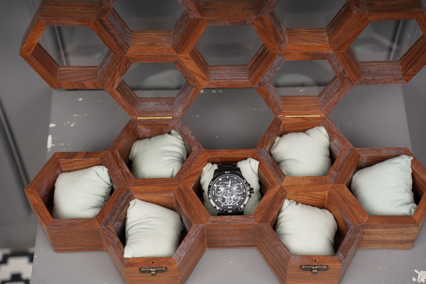 Watch displayed in a wooden hexagonal display case with white cloths.