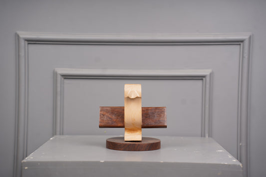 Wooden sculpture on a gray surface with a gray wall background