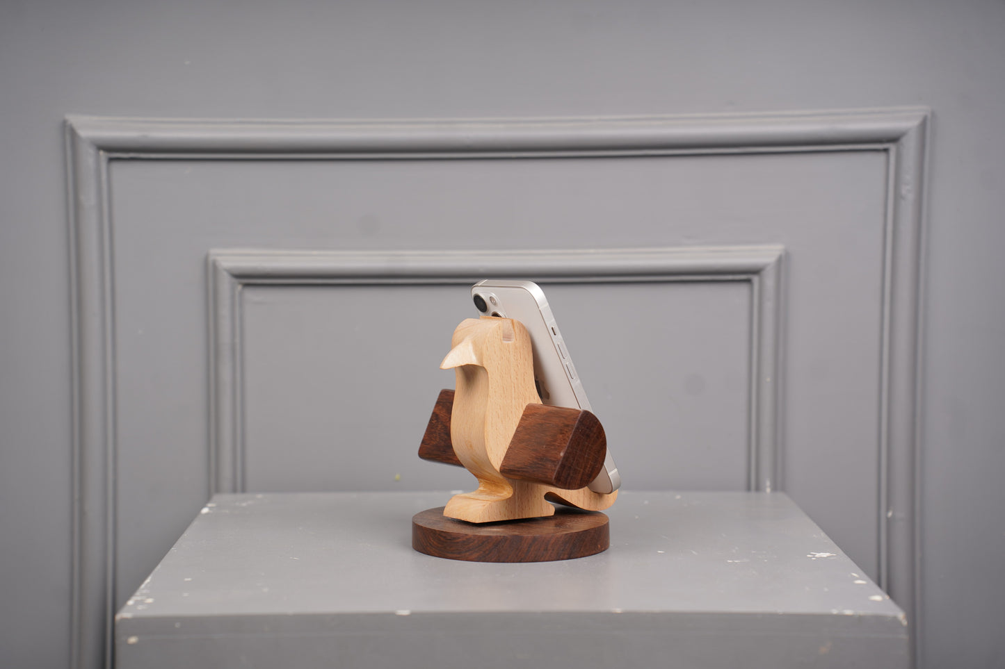 Wooden bird sculpture on a gray surface with a gray background