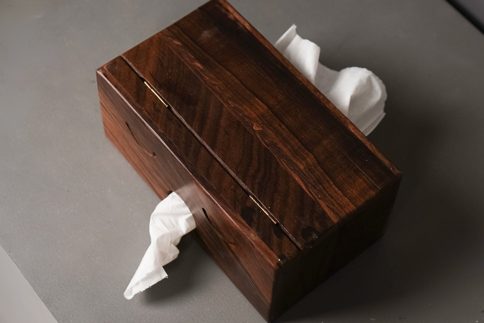 Wooden tissue box with tissues on a gray surface