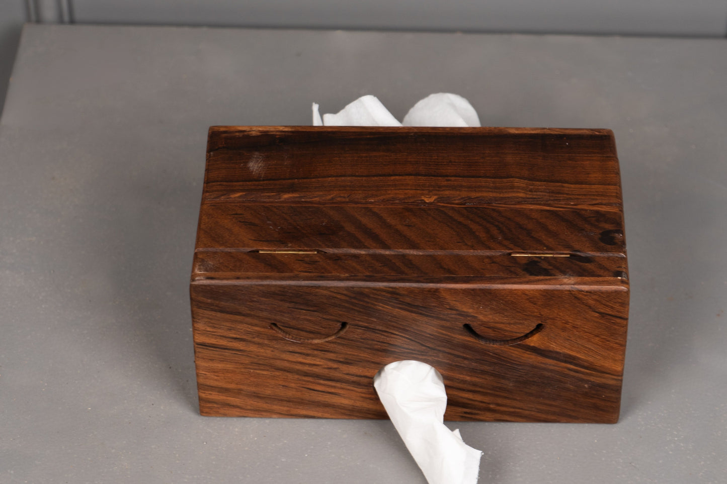 Wooden tissue box with tissues on a gray surface