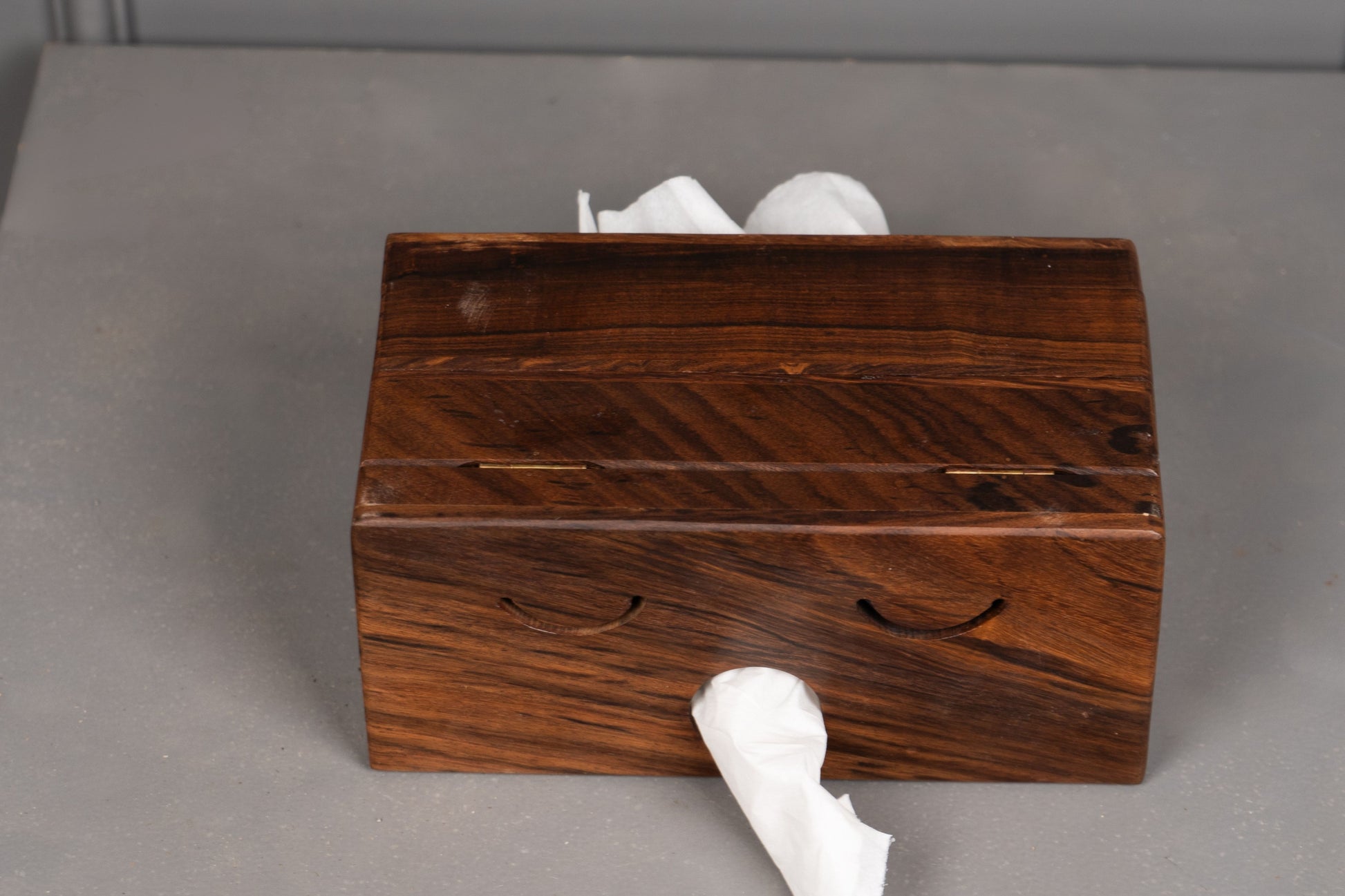 Wooden tissue box with tissues on a gray surface