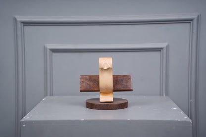 Wooden and gold sculpture on a gray surface with a gray background