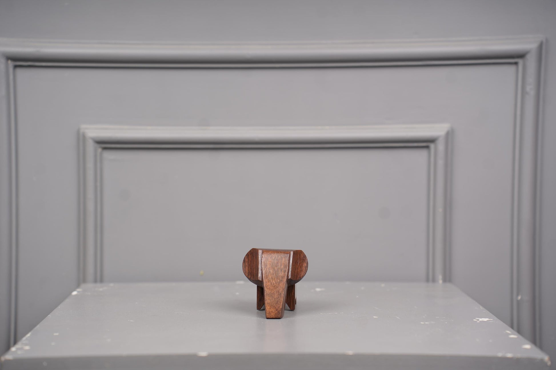 Wooden elephant figurine on a gray surface with a gray background