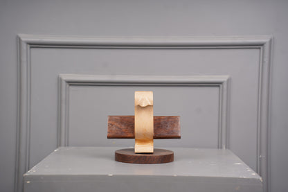 Wooden sculpture on a gray surface with a gray wall background