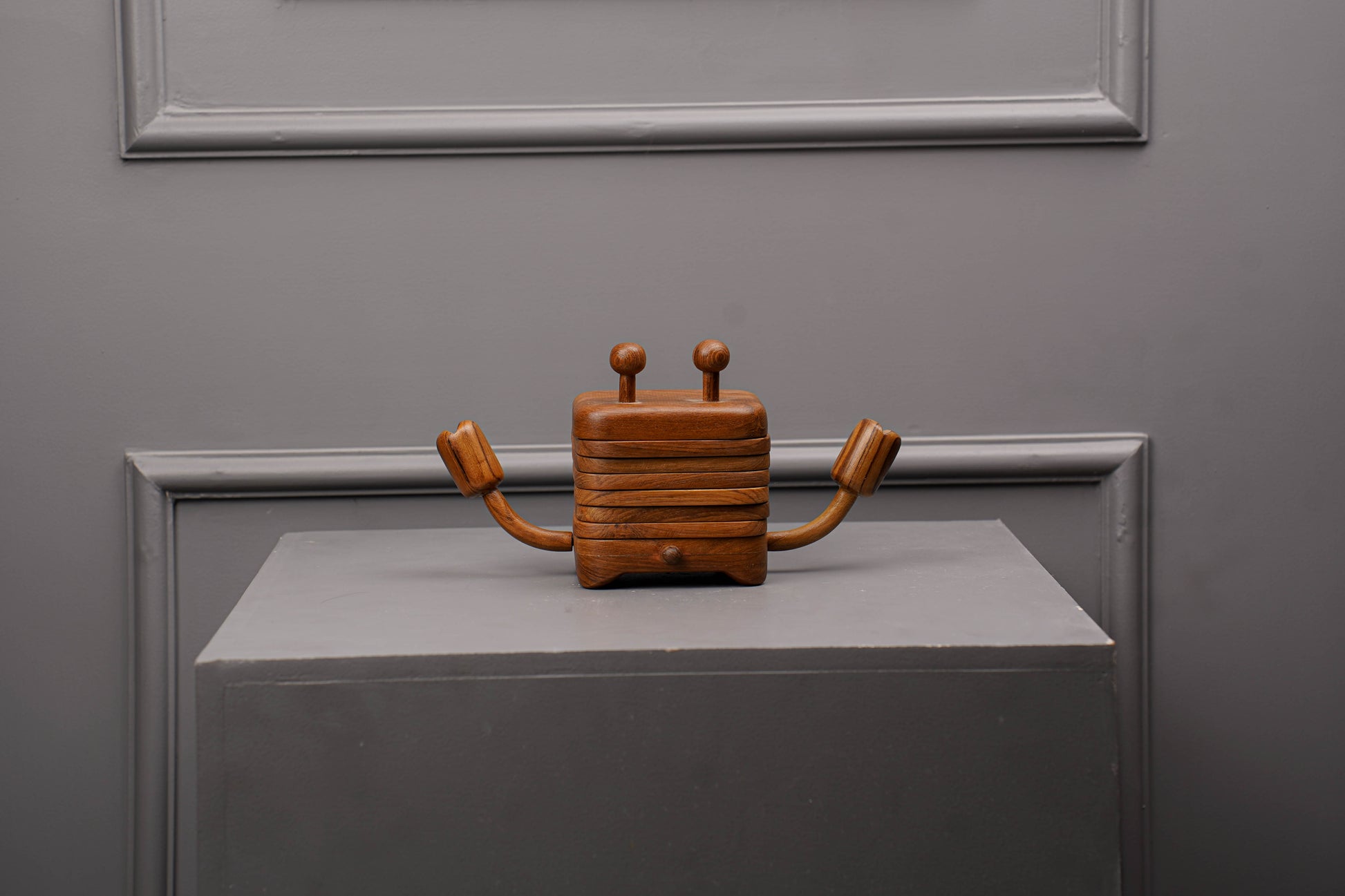 Wooden robot figurine on a gray surface with a gray wall background