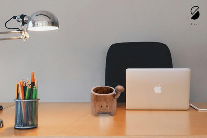 Laptop on a desk with a lamp, mug, and stationery holder.