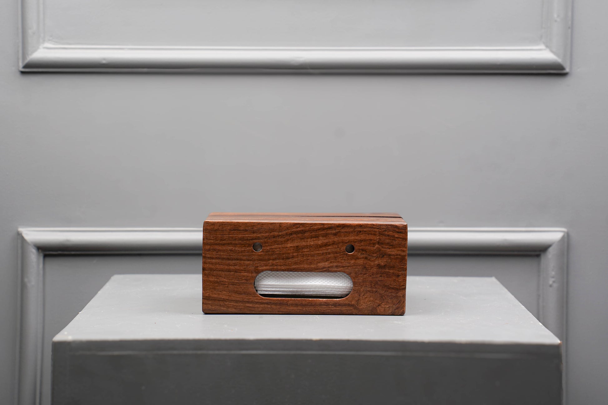 Wooden block with a rectangular cutout on a gray surface with a metallic frame.