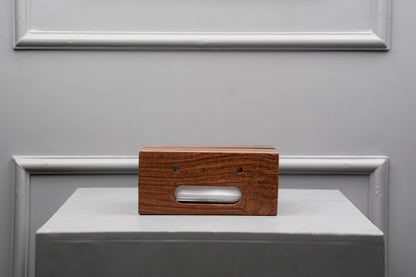Wooden block with a rectangular cutout on a gray surface with a metallic frame.